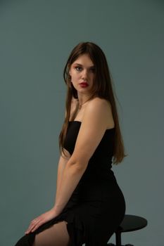 Sophisticated portrait of a woman in black dress against a muted background.