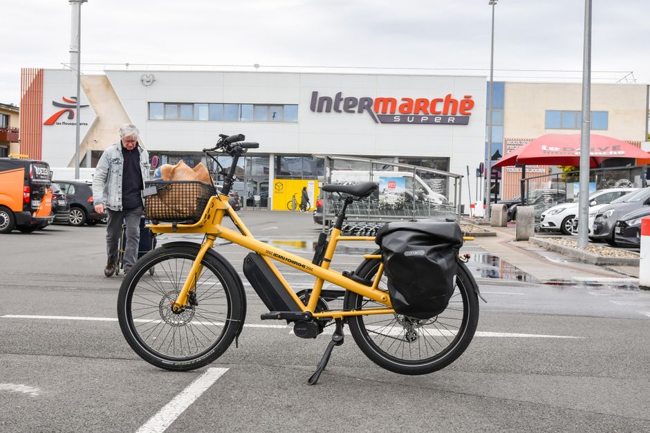 A yellow cargo e-bike parked outside Intermarché supermarket in France, ready for errands.