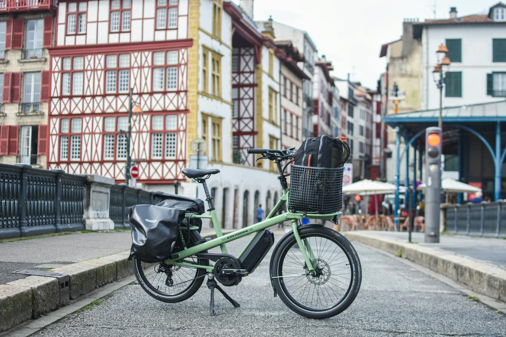 Green cargo bike parked before traditional architecture in France, showcasing urban lifestyle.