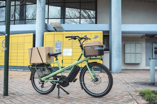 Green electric cargo bike with parcels at La Poste in France, showcasing urban delivery solutions.