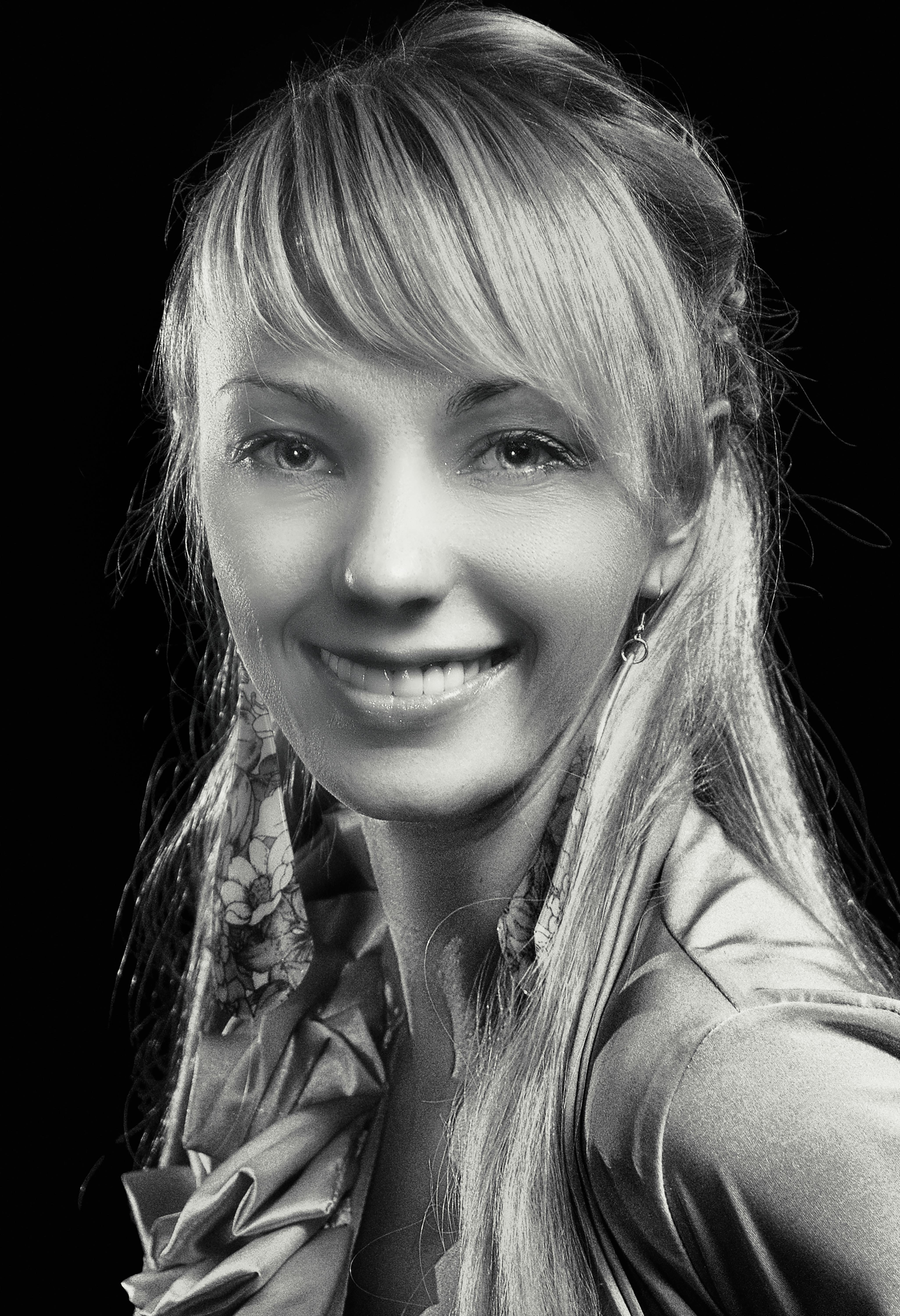 Elegant black and white portrait of a smiling woman with long hair, wearing earrings.
