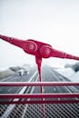 特写镜头中的红色金属桥结构，背景是积雪的高速公路
