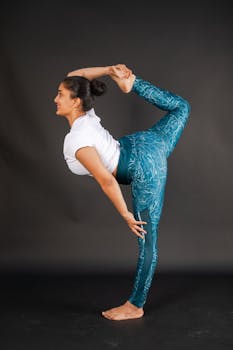A young woman demonstrating flexibility in an advanced yoga pose indoors.