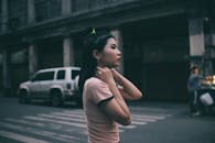 城市街道上，一名年轻女子站在一辆汽车前，肖像略显模糊