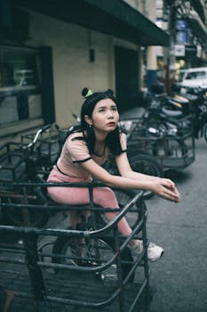 一名年轻女子将双臂搭在金属栏杆上，在城市街道上摆姿势