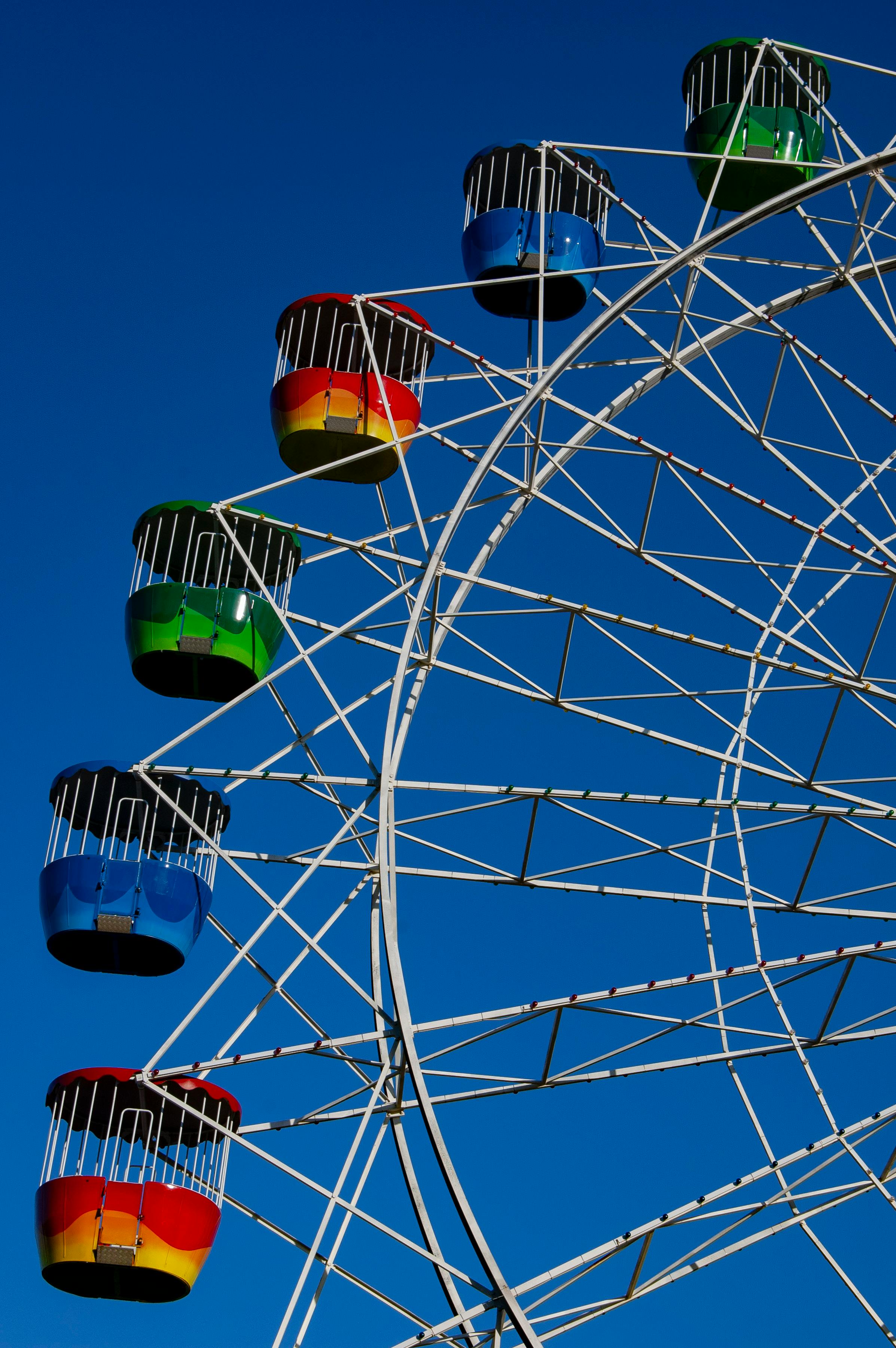 A vibrant ferris wheel with colorful cabins set against a clear blue sky in Sydney, Australia.