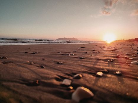 Beautiful sunset over a tranquil beach with gentle ocean waves. Serene and calming scene.