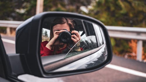 Woman Taking Photo of Car's Side Mirror