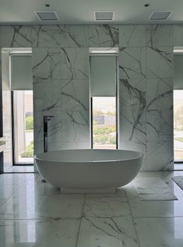 Elegant bathroom with marble finishes and a central freestanding tub, offering a serene spa-like atmosphere.