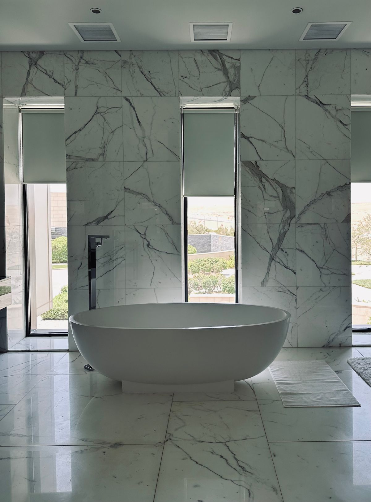 Luxury coastal bathroom with a freestanding tub and marble finishes