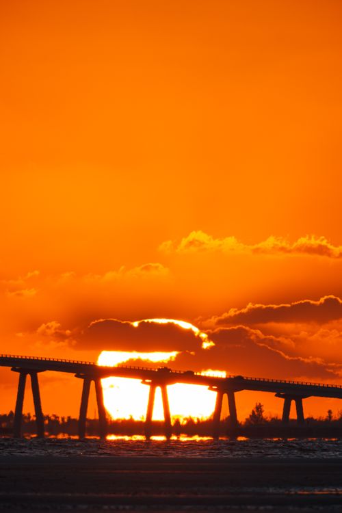 Free A striking sunset behind a bridge silhouette in Florida, USA, with vivid orange hues. Stock Photo