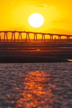 Stunning sunset view with a bridge silhouette in Florida, casting reflections on the ocean.