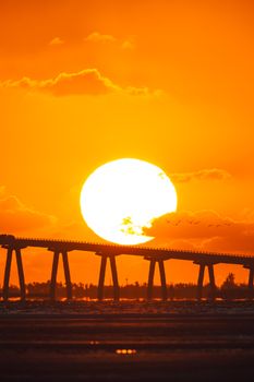Stunning sunset view over a bridge in Florida, highlighting vibrant orange hues and silhouettes.
