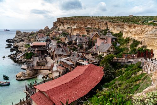 Free Charming coastal village landscape in Malta, showcasing colorful architecture by cliffs and azure waters. Stock Photo