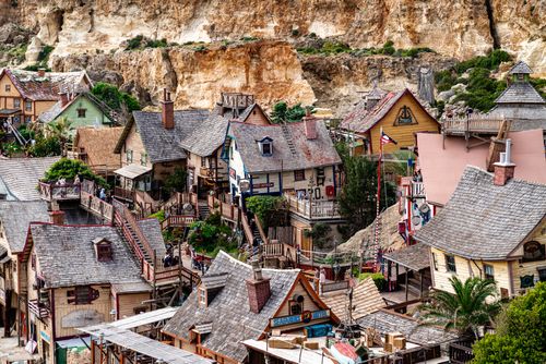 Free Charming village with wooden houses set against rocky cliffs in Malta, perfect for adventure seekers. Stock Photo