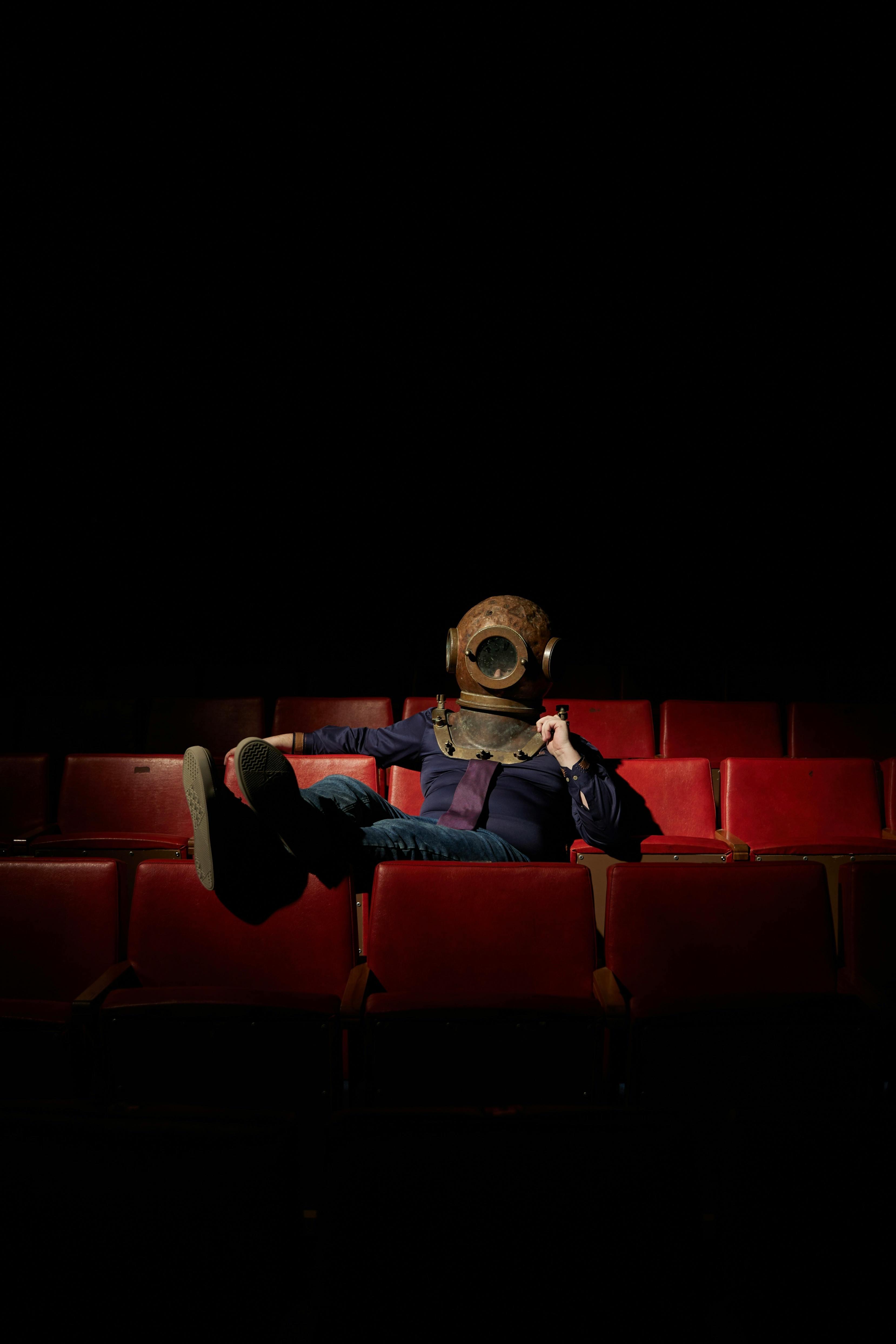 Ilmainen Sukelluskypärässä istuva henkilö yksin teatterissa herättäen mysteeriä. Kuvapankkikuva