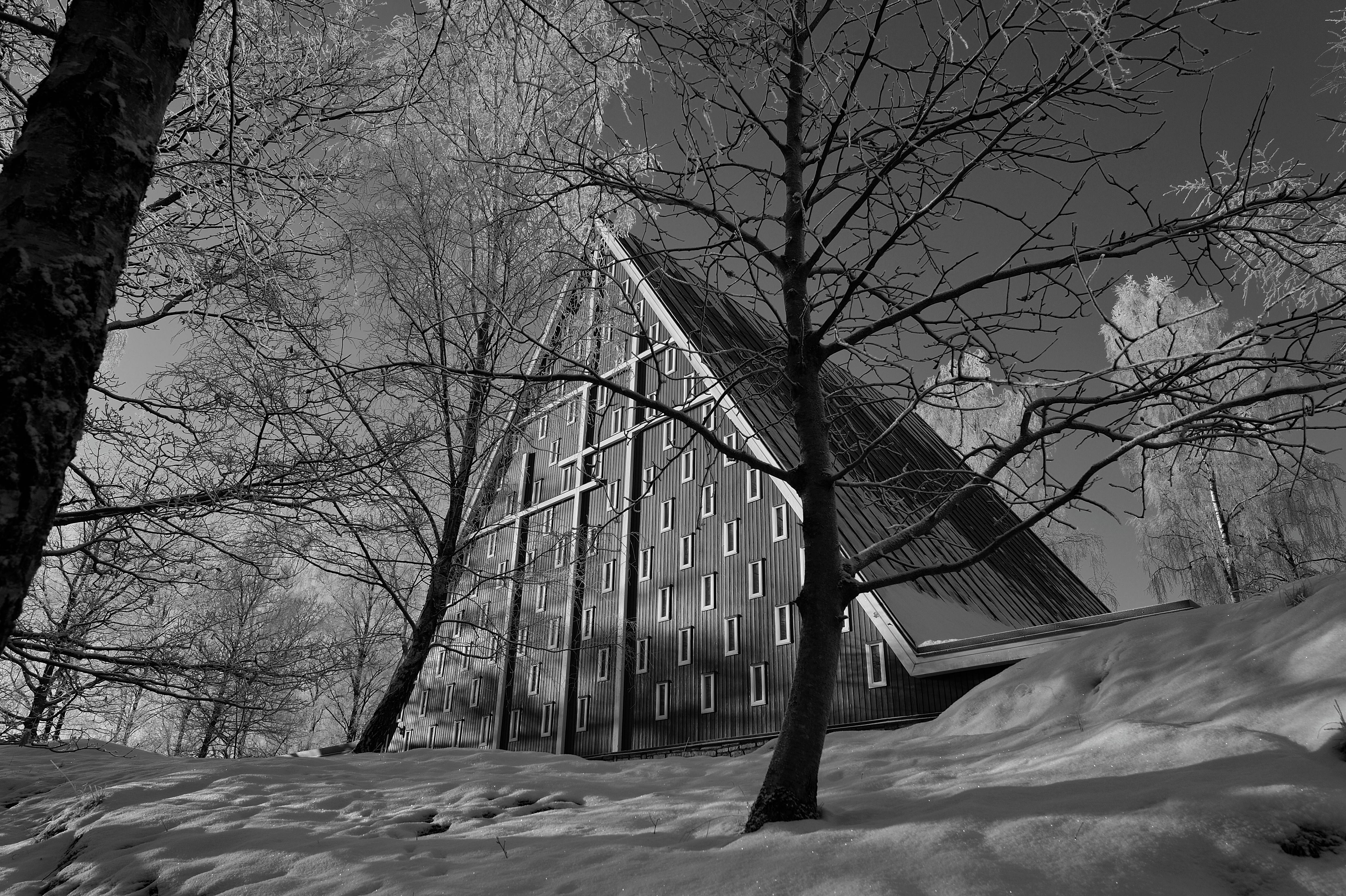 A modern A-frame church surrounded by snow in a serene winter setting.