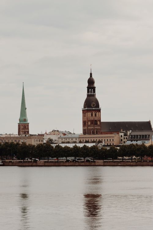 Free A tranquil view of Riga's iconic cathedral and architecture reflected in the river. UNESCO heritage site. Stock Photo