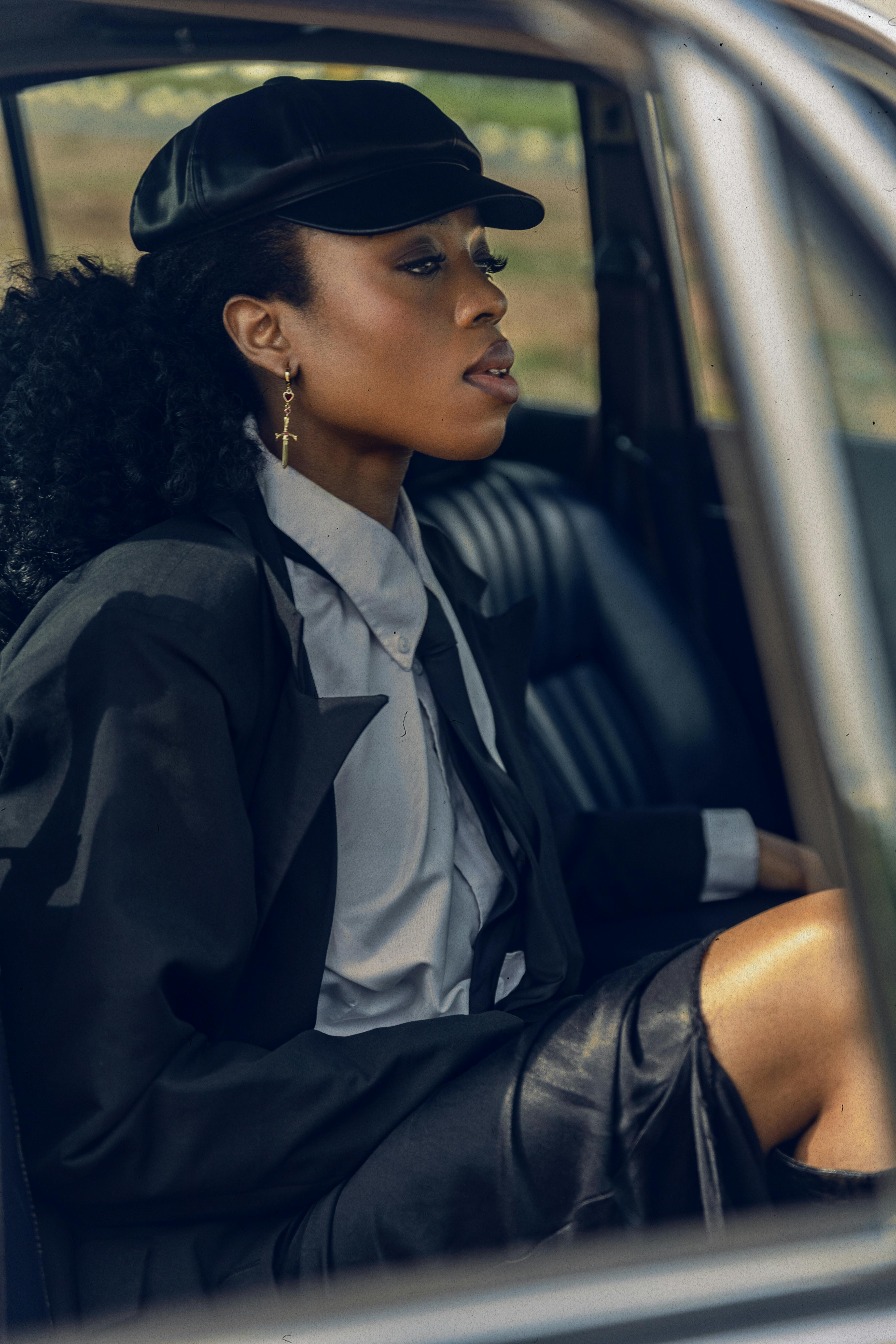 Elegant woman in sophisticated attire sits in classic car, exuding style and grace.