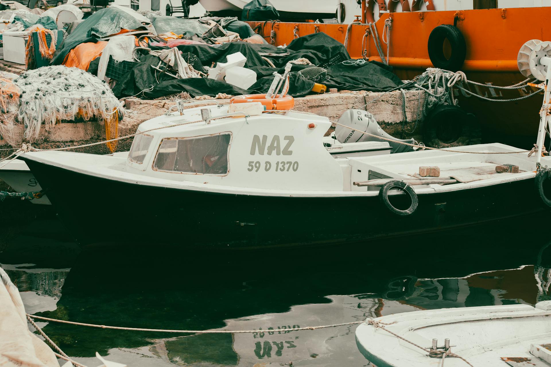 Fishing boat docked at harbor with colorful nets and equipment, creating a rugged maritime scene.