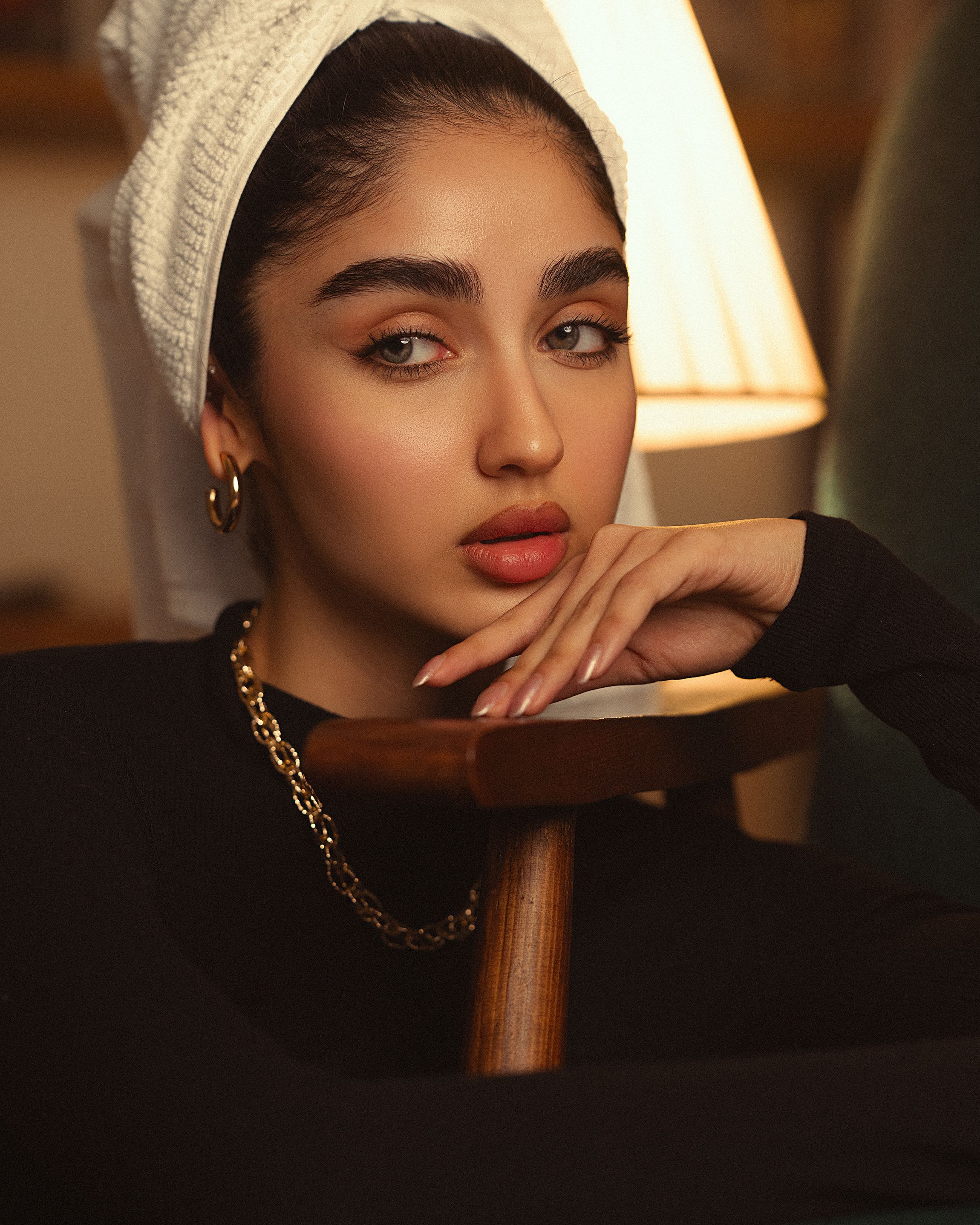 Captivating portrait of a woman with a gold necklace, set against a warm background.