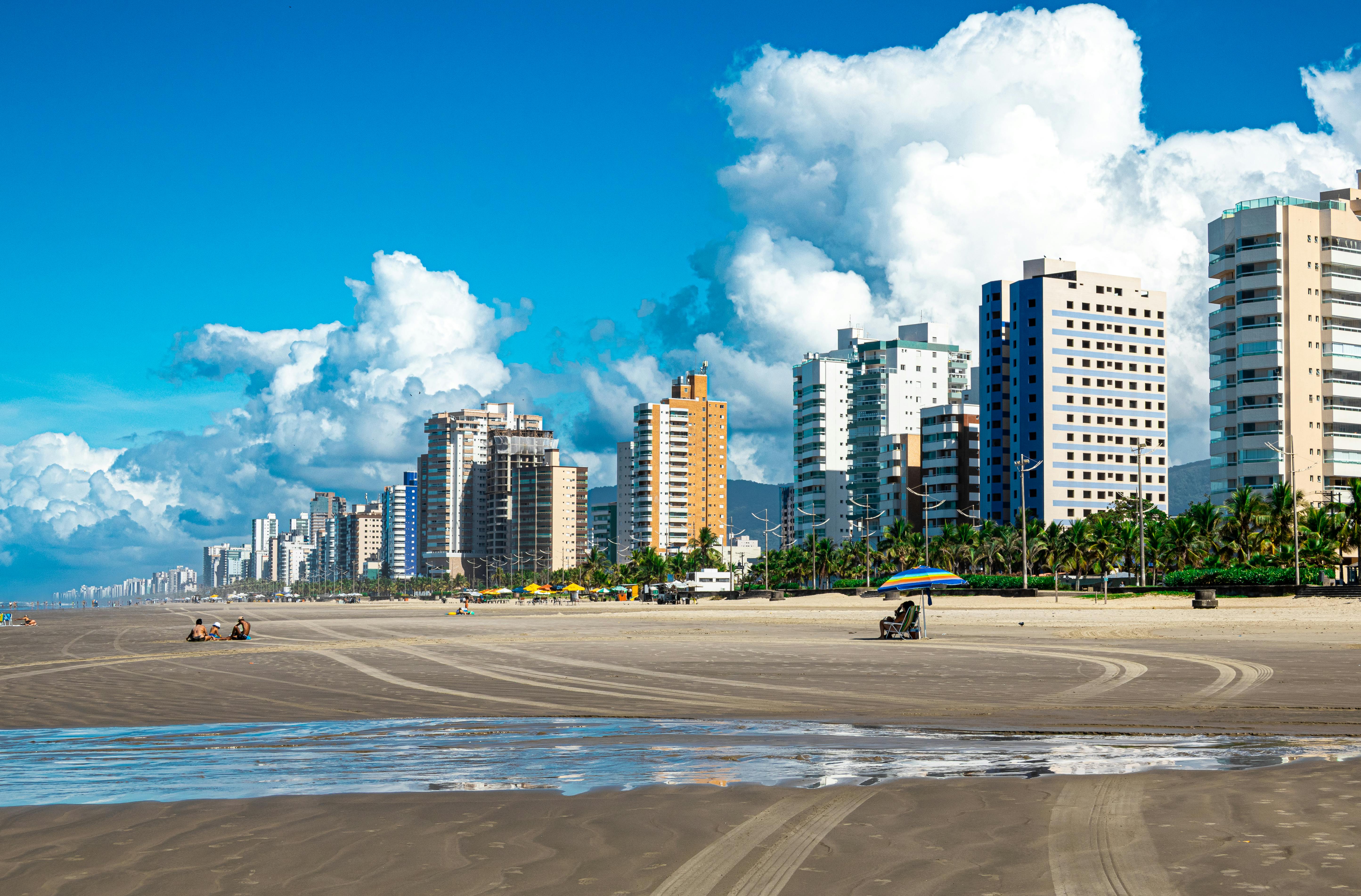 A vibrant view of Praia Grande's beachfront skyline with towering apartments and serene sandy beach beneath a clear blue sky.