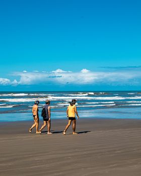 Group enjoying a sunny walk on Praia Grande's sandy shore in São Paulo, Brazil.