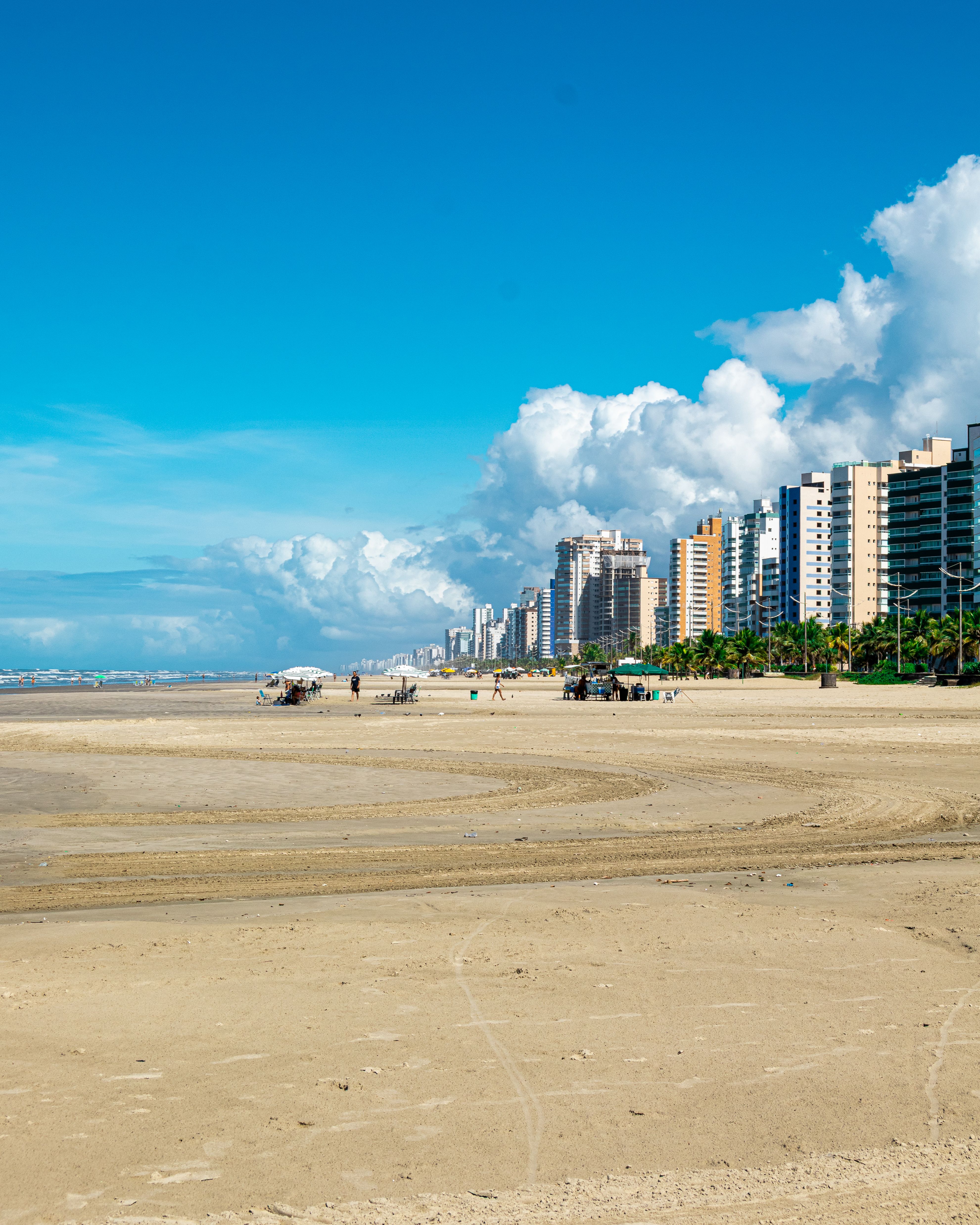 Stunning view of Praia Grande's urban beach with soft sand and a city skyline under a clear blue sky.
