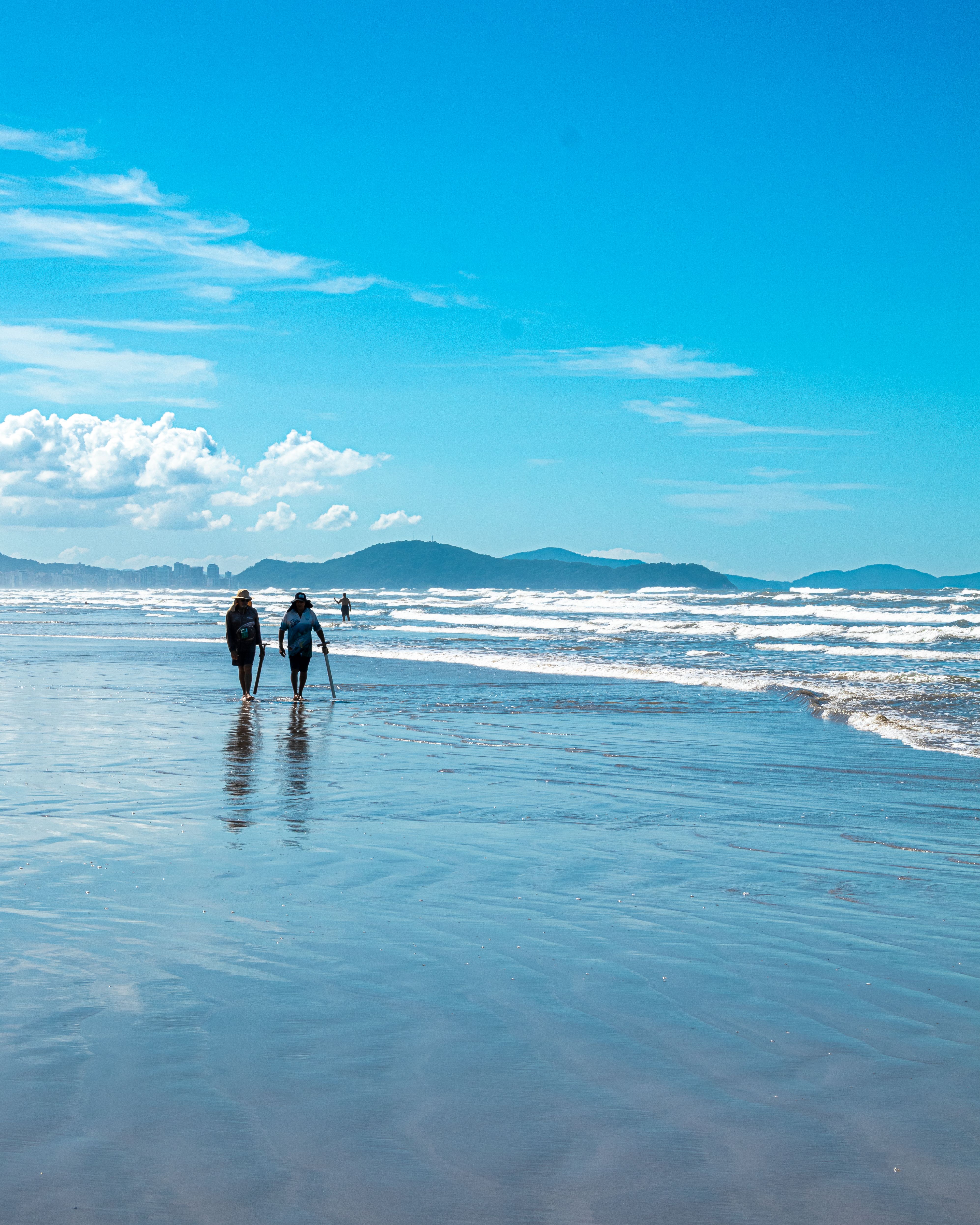 A calming beach walk on Praia Grande in São Paulo, Brazil under a clear blue sky.