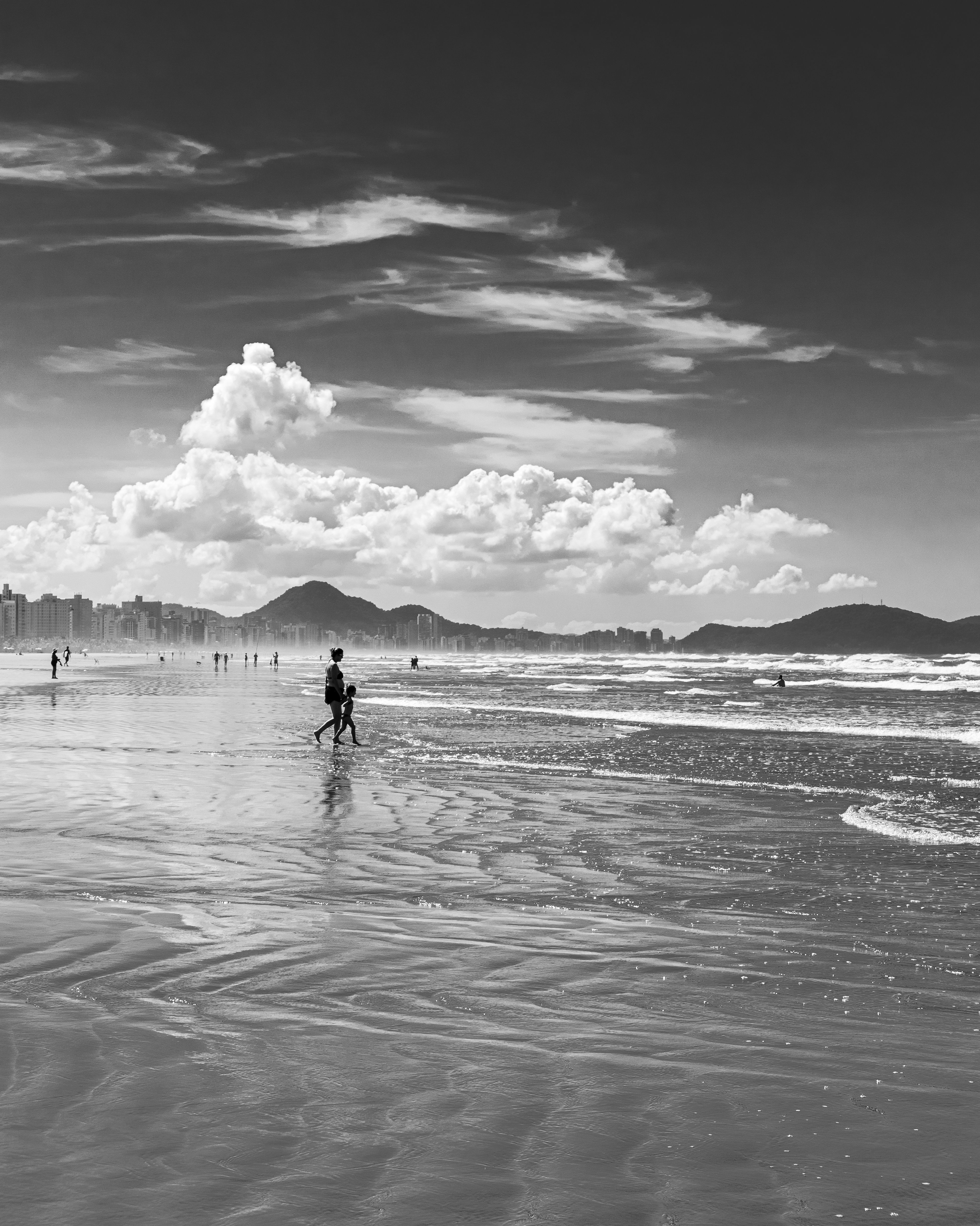 Black and white photo of Praia Grande's coastline with people walking along the beach.