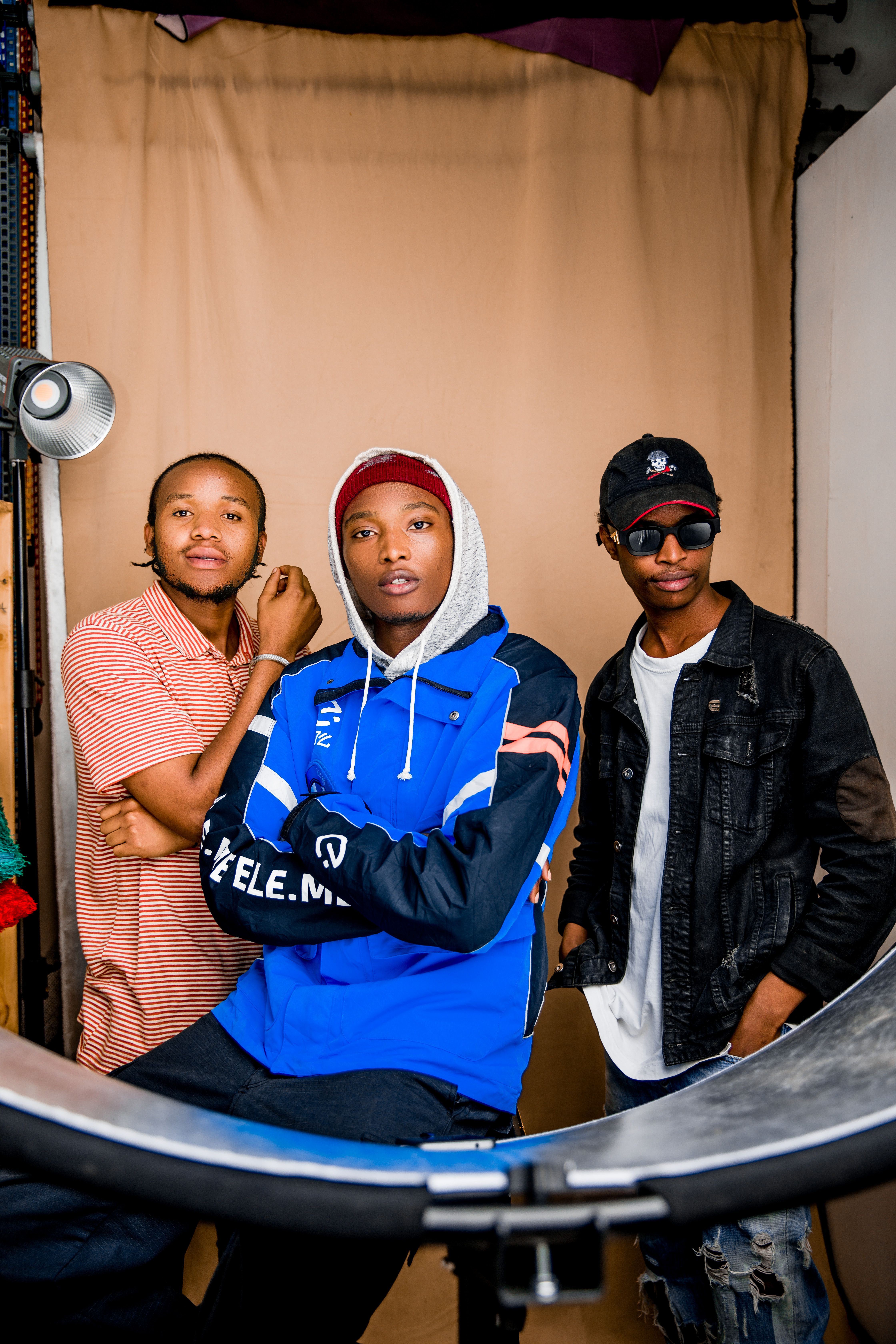 Three young adults in casual wear posing indoors with an urban vibe.
