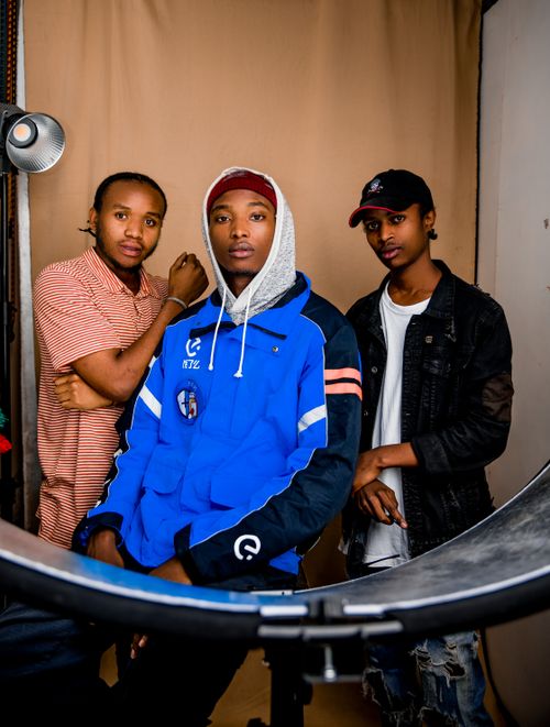 Free Three young men posing confidently in a studio. Casual fashion and cool expressions. Stock Photo