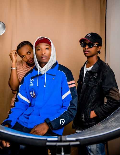 Free Three fashionable young men posing casually indoors with cool attire and expressions. Stock Photo