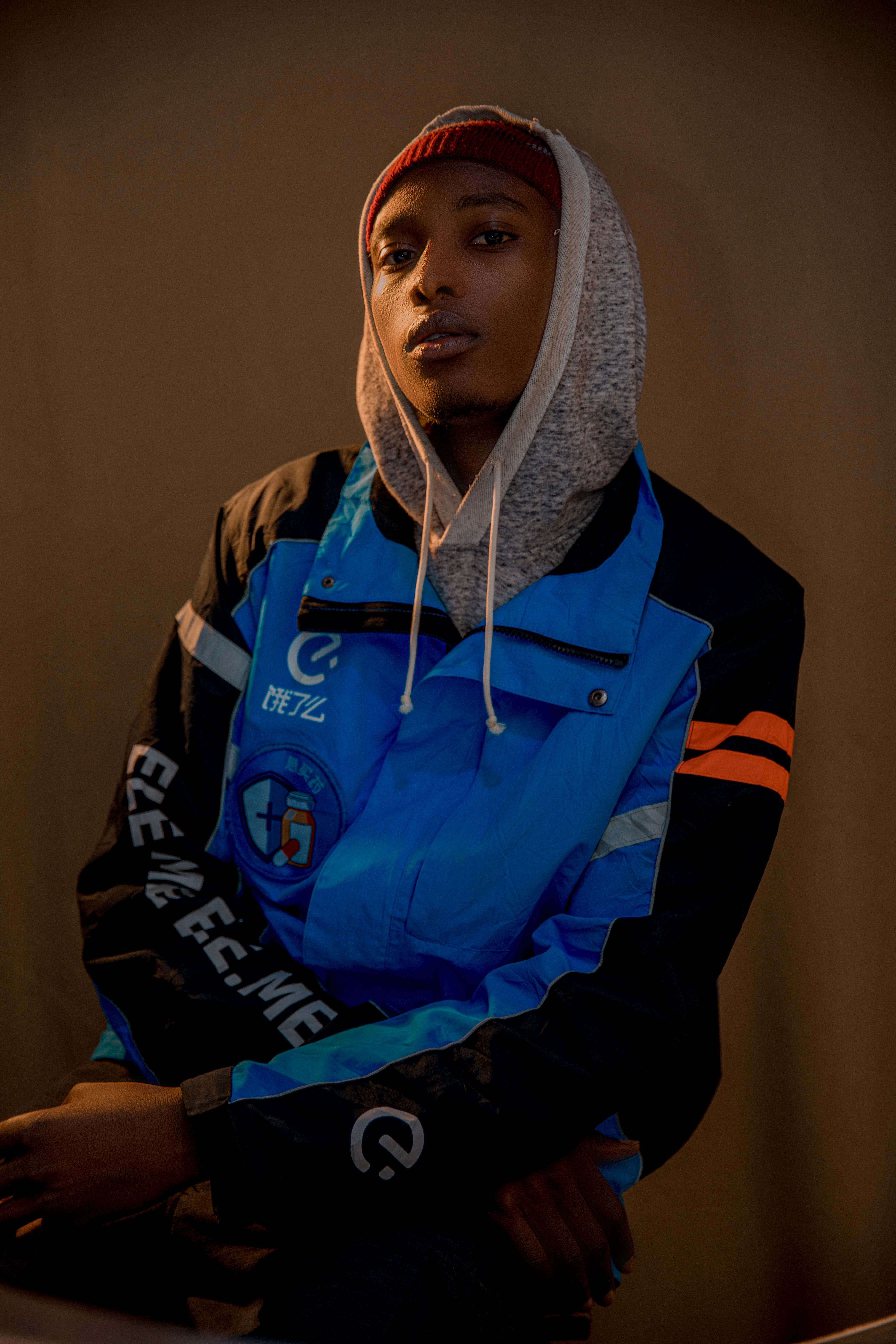 Close-up of a person wearing a colorful blue jacket and hoodie indoors.