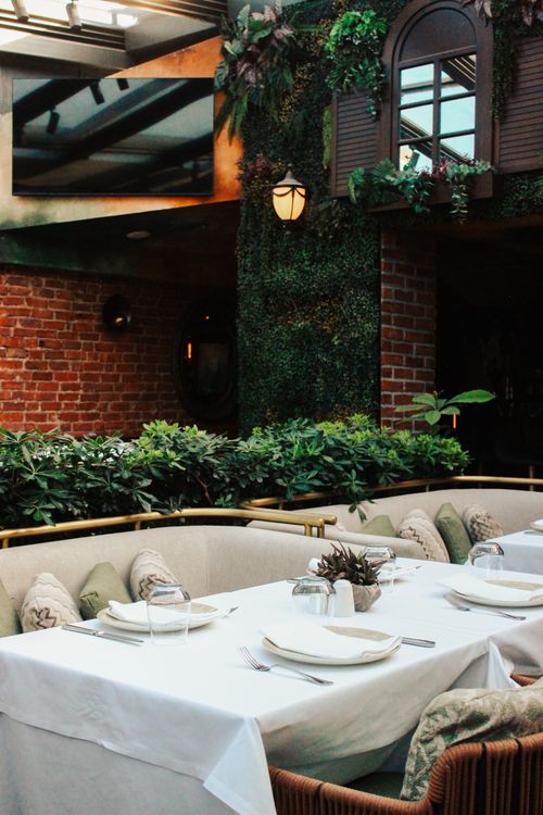 Free Chic outdoor dining area surrounded by lush plants and elegant decor. Stock Photo