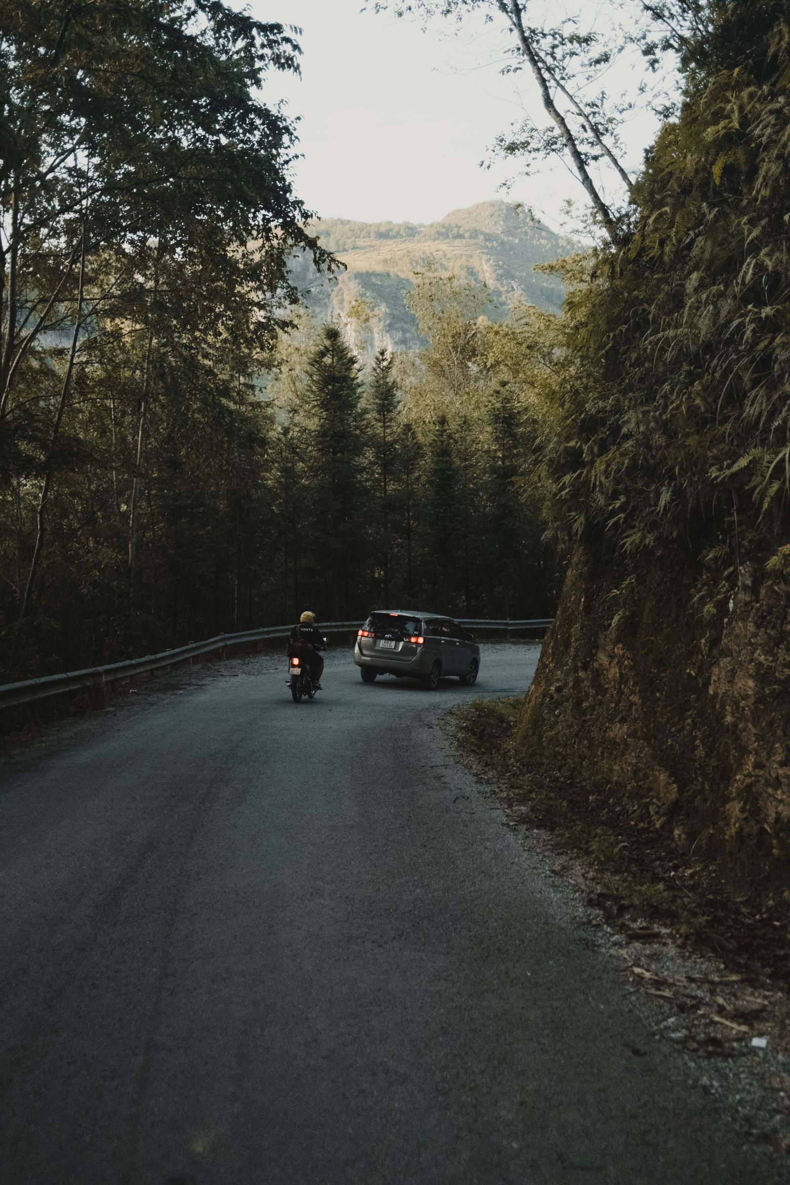 Mountain road with car and motorbike showing how accommodation and logistics matter on a Ha Giang tour