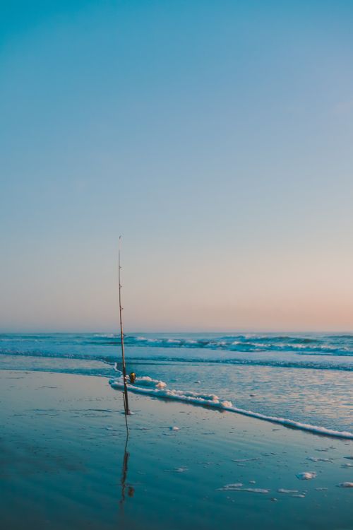 Free A tranquil beach scene with a lone fishing rod under a pastel sky in Mar del Tuyú, Argentina. Stock Photo