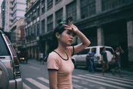 一名年轻女子站在繁忙的城市街道旁，正穿过人行道