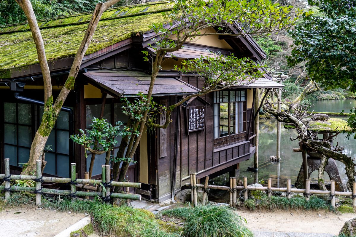 Traditional Japanese tea house by a serene lake, evocative of Shizuoka tea country