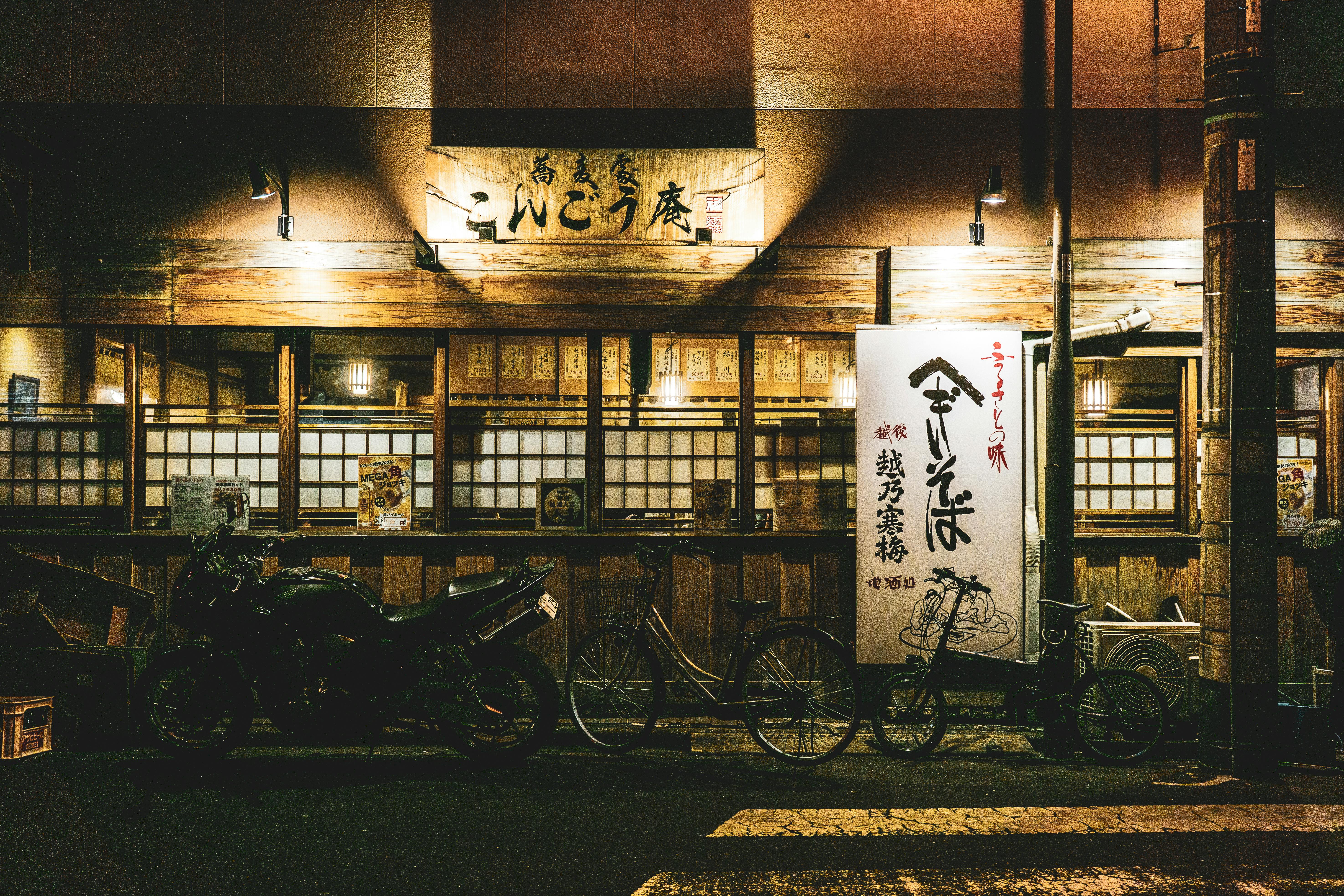 Illuminated Japanese restaurant facade with parked bicycles at night, showcasing authentic cultural elements.