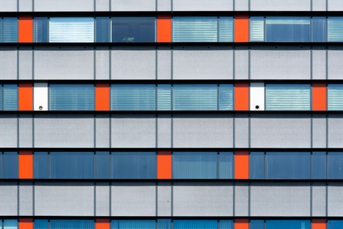 Free Minimalist facade of a modern building with geometric windows and bold red accents. Stock Photo