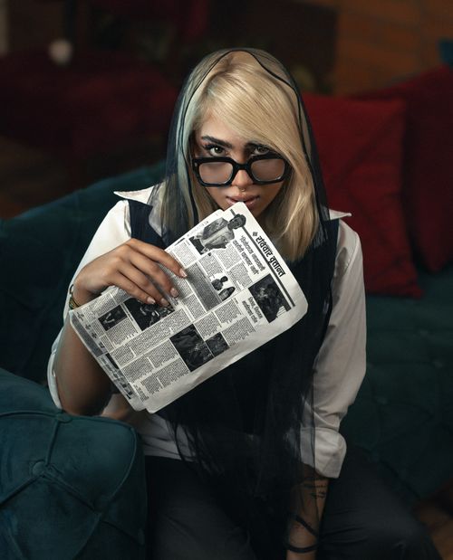 Free Blonde woman with glasses reads a newspaper in a cozy setting, exuding a vintage vibe. Stock Photo