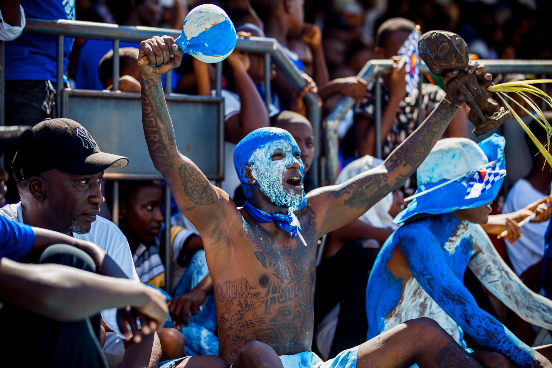 Dynamic scene of painted fans energetically supporting their team in a packed stadium.