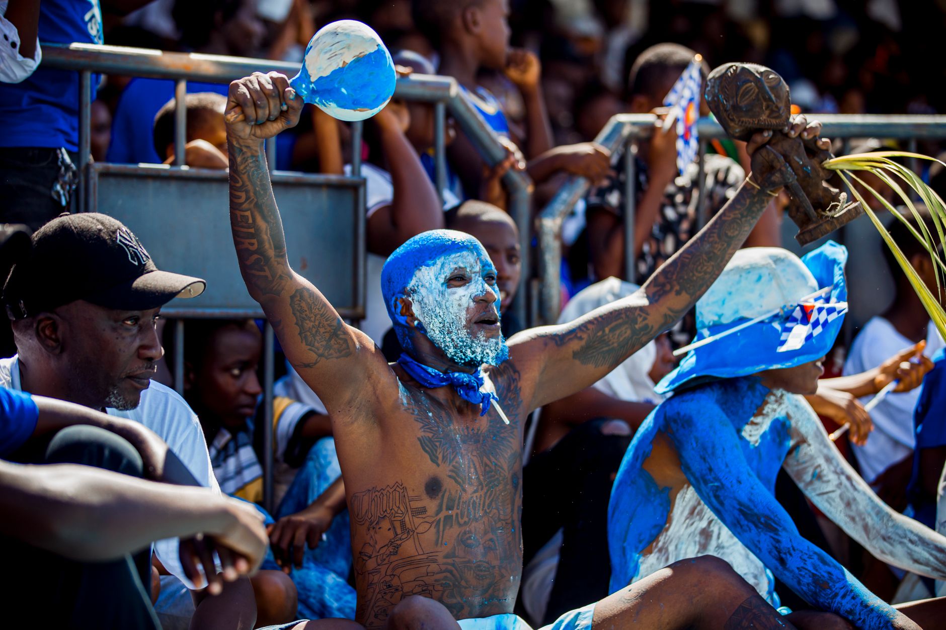 Vibrant scene of a spirited carnival with painted participants cheering energetically.