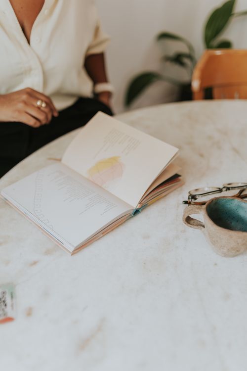 Free An open book on a marble table next to coffee, evoking a serene morning reading vibe. Stock Photo
