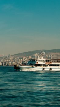 Ferry cruising on Izmir Bay with a panoramic view of the city's skyline and coastal landscape.