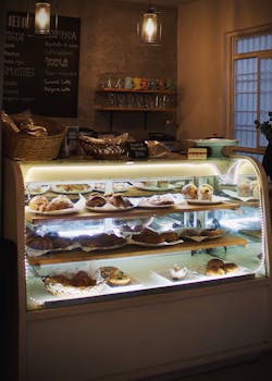 Warmly lit bakery display filled with pastries in a cozy Mérida café.