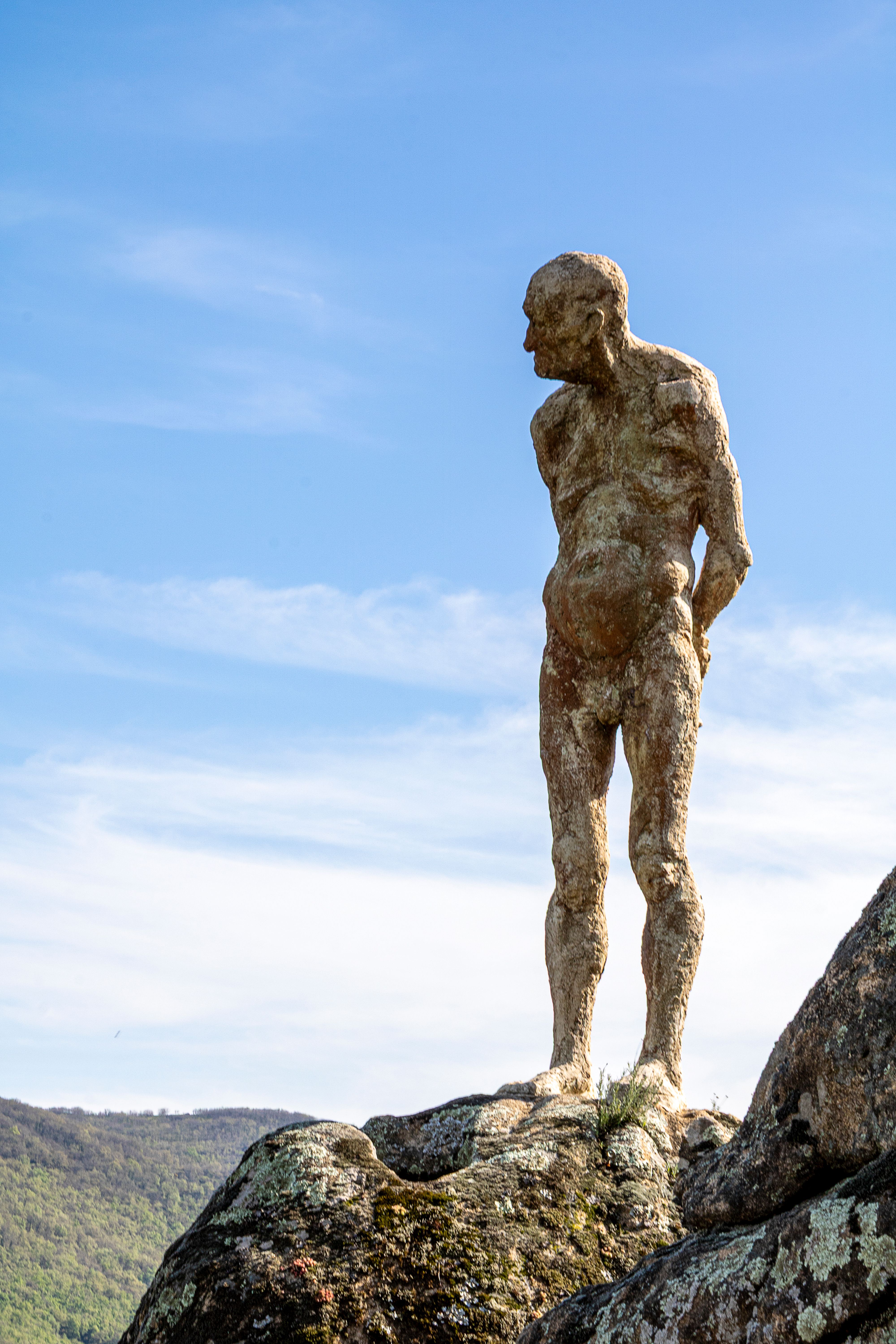 A weathered stone statue stands against a vibrant blue sky in El Torno, Spain.
