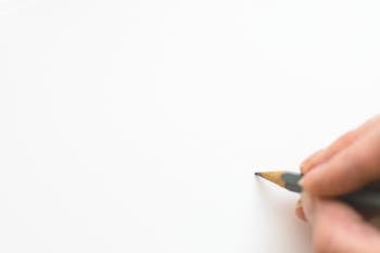 Close-up of Hand Holding Pencil over White Background