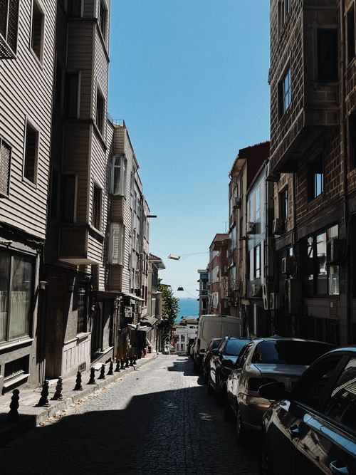Free Charming İstanbul street leading to the sea, showcasing rich architecture under a clear blue sky. Stock Photo